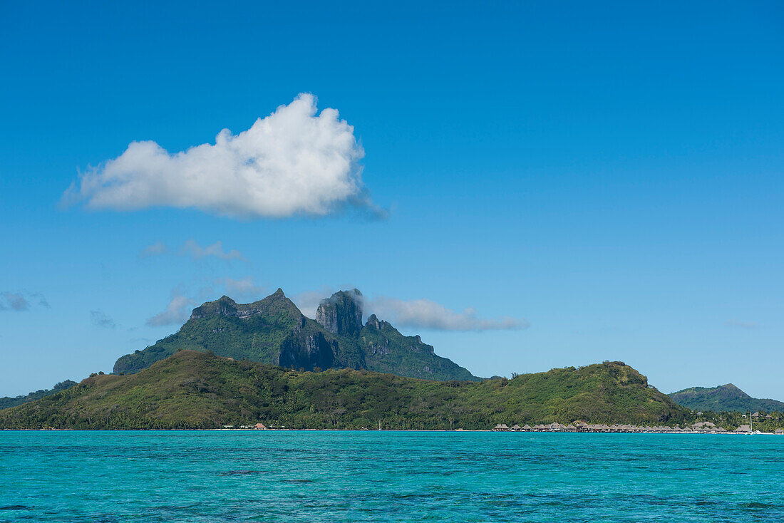 Massive Berge überragen die Insel während Überwasser Bungalows eines Luxusresorts entlang die Küste säumen, Bora Bora, Gesellschaftsinseln, Französisch-Polynesien, Südpazifik
