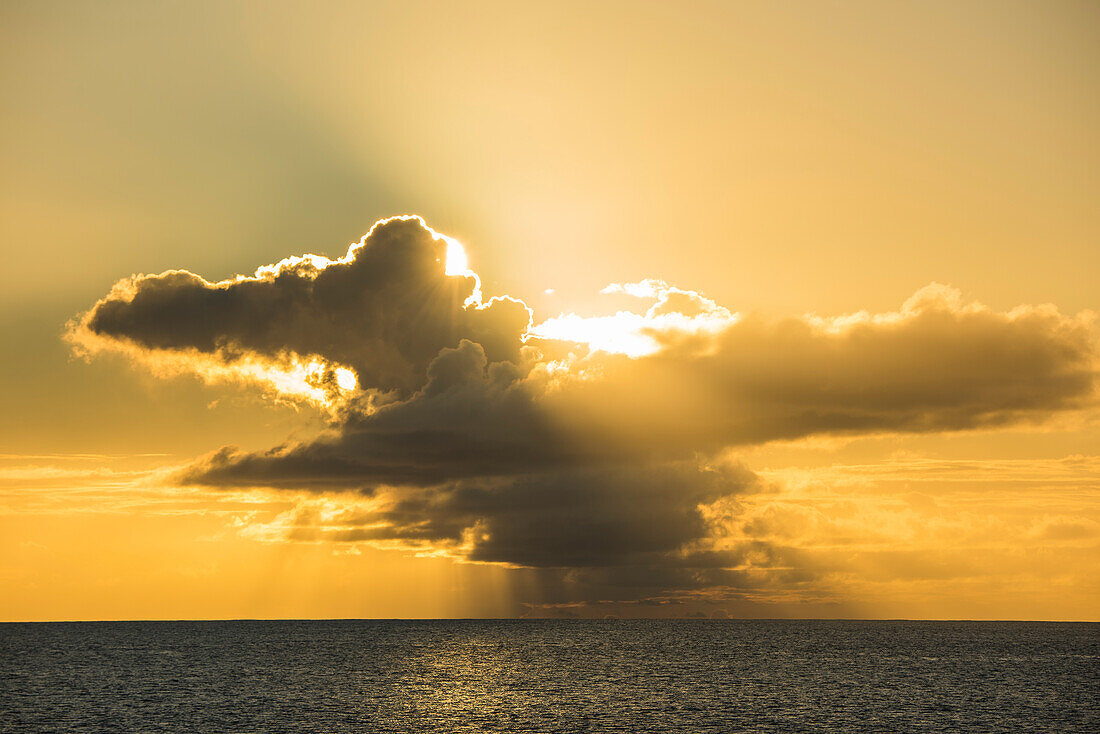 Die späte Nachmittagssonne bricht durch Gewitterwolken und erzeugt ein warmes orange-gelbes Licht, Bora Bora, Gesellschaftsinseln, Französisch-Polynesien, Südpazifik