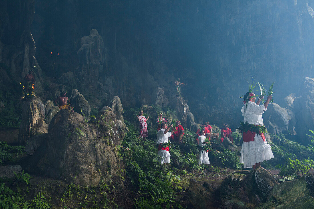 Einheimische, einige in Tracht, begrüßen die Touristen am Eingang zu einer riesigen Höhle, Rurutu, Austral-Inseln, Französisch-Polynesien, Südpazifik