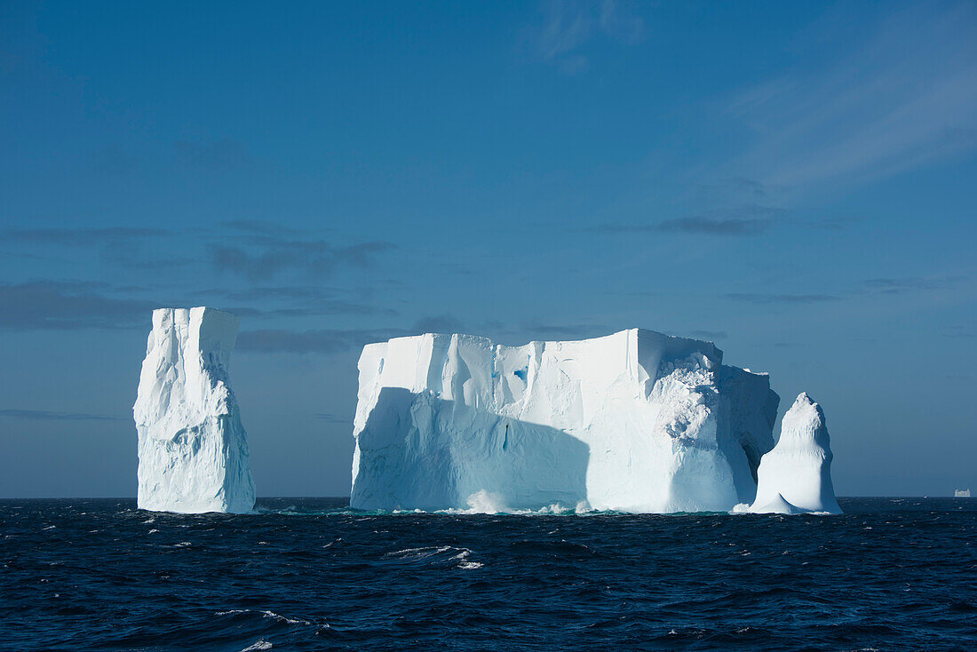 Ein Eisberg, einst viel größer, aber jetzt mit drei Türmen, schwimmt im offenen Meer, in der Nähe von South Shetland Islands, Antarktis