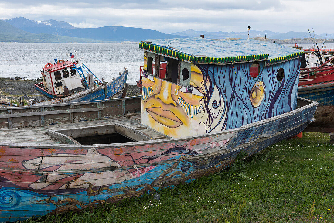 Kreativ bemalte, gestrandete Boote liegen am Ufer in der Nähe des Hafens, Puerto Williams, Magallanes y de la Antartica Chilena, Patagonien, Chile