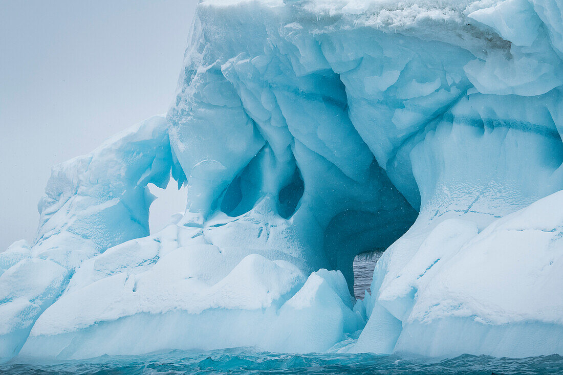 Ein seltsam geformter Eisberg mit zahlreichen Löchern und Tunneln schwebt wie eine moderne Skulptur auf offener See, Brown Bluff, Weddell Sea, Antarktische Halbinsel, Antarktis