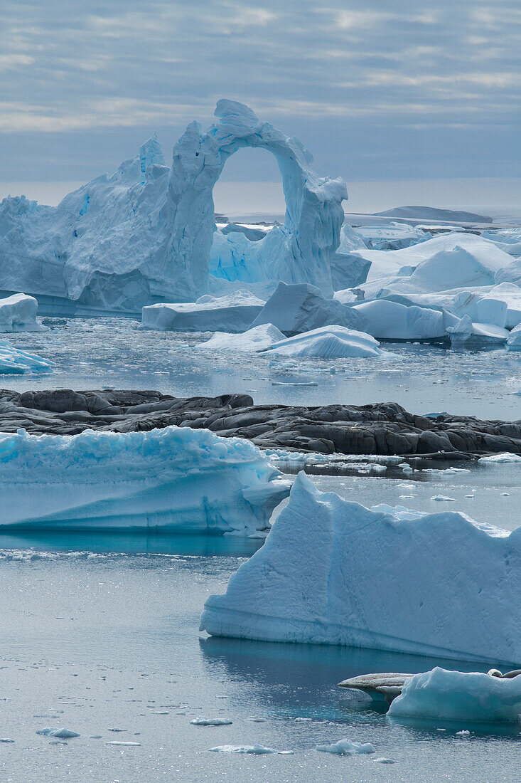 One of numerous icebergs features an unlikely towering archway at least 20 meters high, Pleneau Island, Wilhelm Archipelago, Antarctica