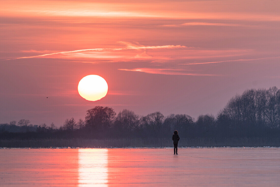 Roter Sonnenuntergang im Winter über einem gefrorenen See in Deutschland