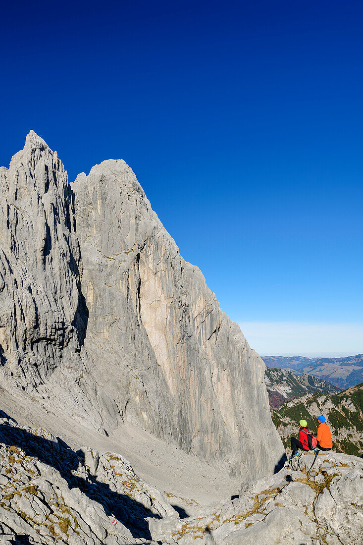 Man and woman sitting at Ellmauer Tor and looking towards Christaturm and Fleischbank, Ellmauer Tor, Wilder Kaiser, Kaiser range, Tyrol, Austria