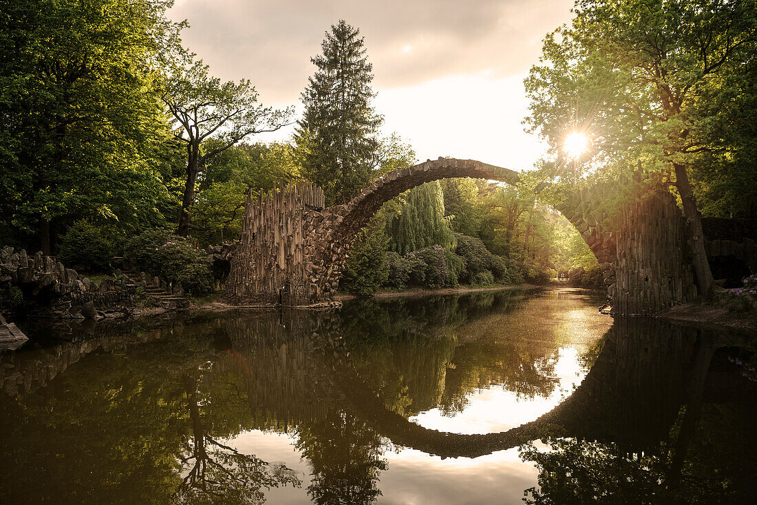 Rakotz Bridge lit by backlight of setting sun, Azalea and rhododendron park Kromlau, Gablenz, Goerlitz district, Saxony, Germany