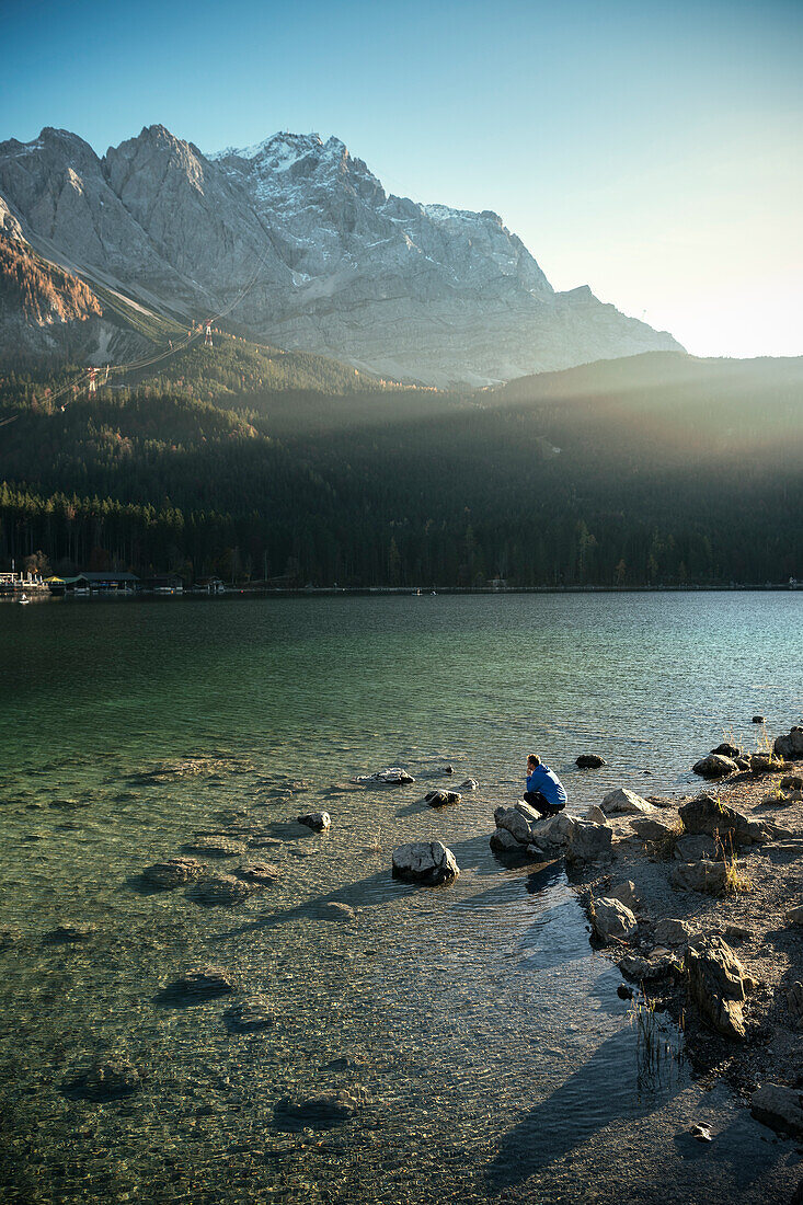 man enjoys view at Eibsee below Zugspitze mountain, Grainau community, Garmisch-Partenkirchen, Bavaria, Alps, Germany