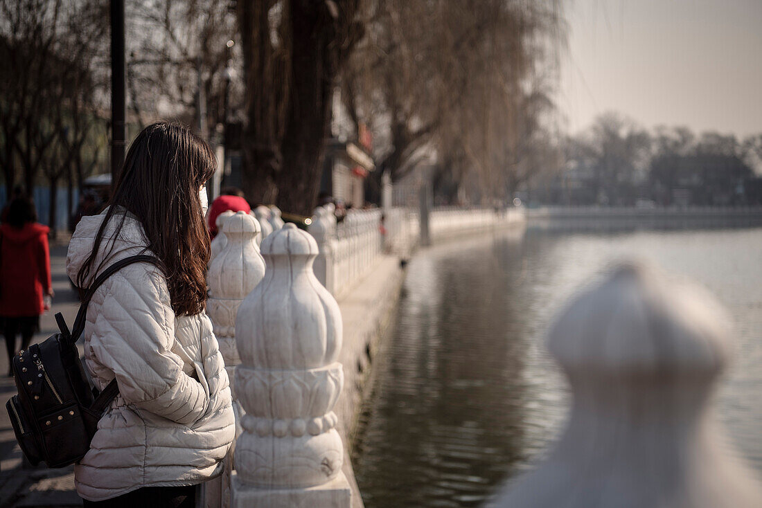 chinese woman with air mask looking at Houhai Lake, Beijing, China, Asia
