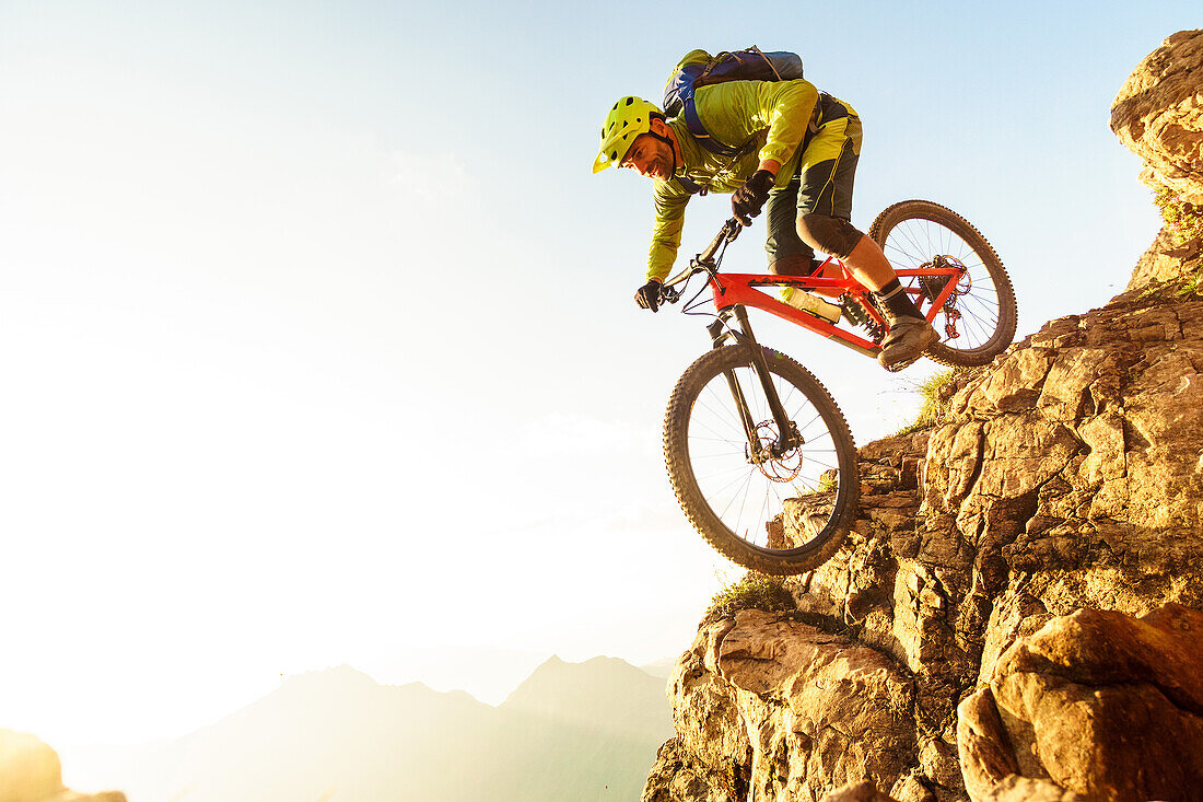 Middle aged man drops a steep rock clif on his mountainbike, Kitzbühel Alps, Tyrol, Austria