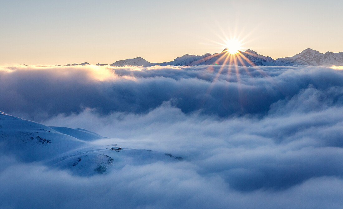 Sonnenaufgang über dem Wolkenmeer, Hütte auf Hügel  steht über den Wolken, Brenner Berge, Stubaier Alpen, Tirol, Österreich