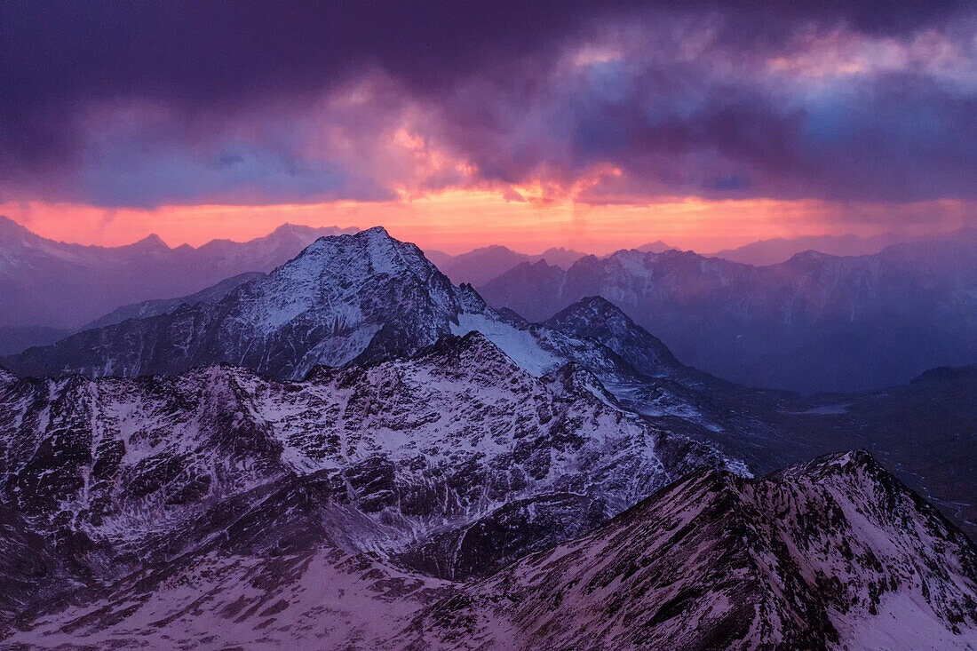 Eindrucksvoller Sonnenuntergang über eingeschneiten Berge, Sturm, Blick von der Biwakschachtel am Piz Tresero, Valfurva, Lombardei, Südtirol, Italien