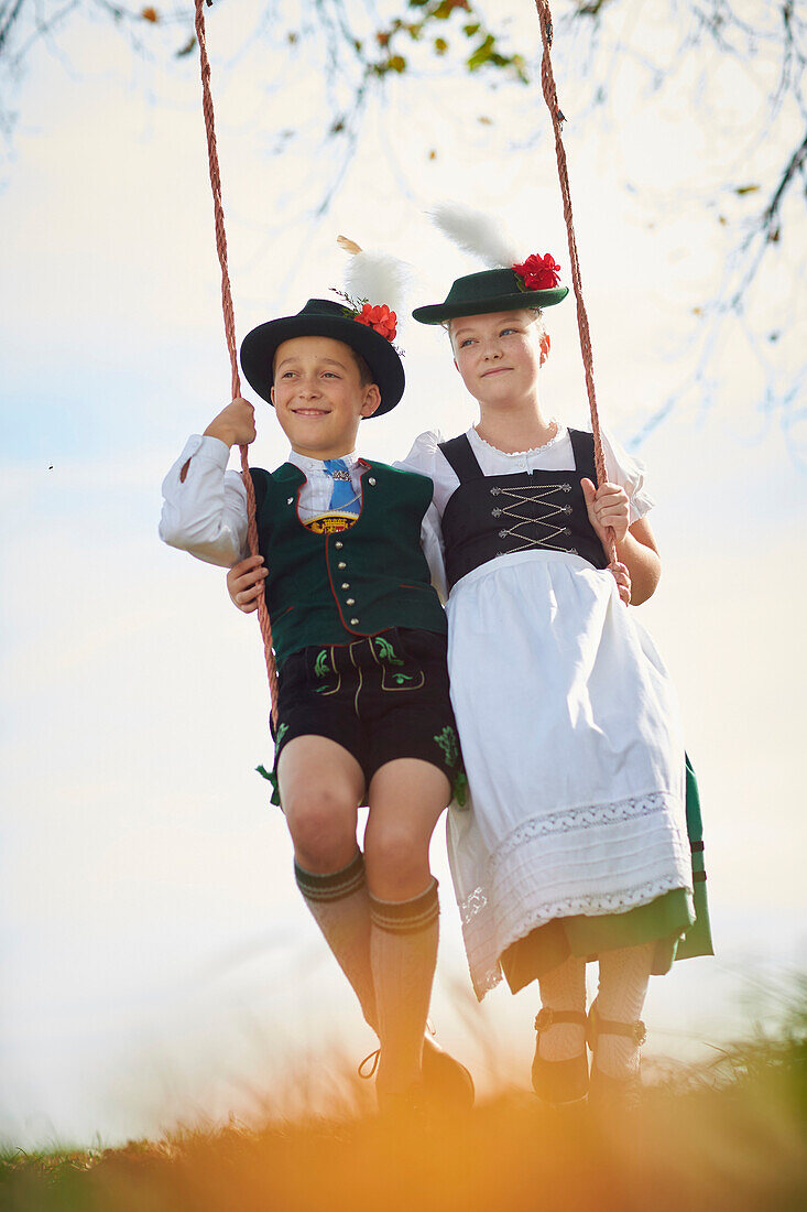 Junge und Mädchen auf Schaukel, Trachtenverein Seeröserl Ammerland Münsing , Ammerland Münsing, Bayern, Deutschland