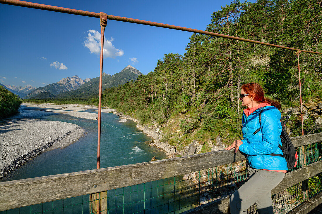 Woman standing on suspension bridge and looking into river Lech and valley of Lech with Lechtal and Allgaeu Alps, Lechweg, Forchach, valley of Lech, Tyrol, Austria