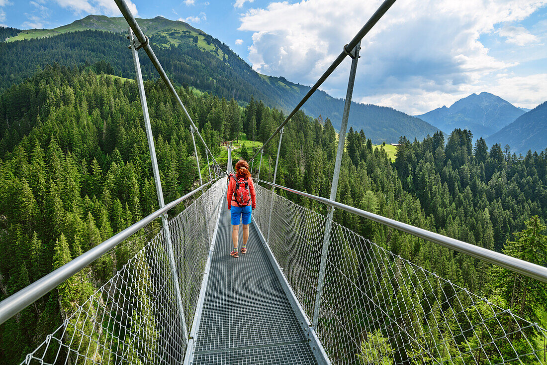 Woman walking on suspension bridge, Holzgau, Lechweg, valley of Lech, Tyrol, Austria