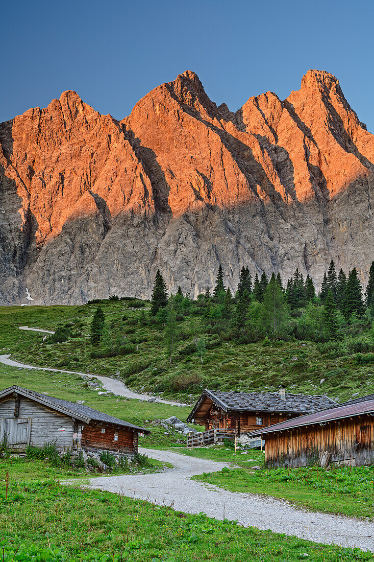 Alpine huts of Ladizalm with rockfaces of Laliderer Waende in alpenglow, Ladizalm, Natural park Karwendel, Karwendel, Tyrol, Austria