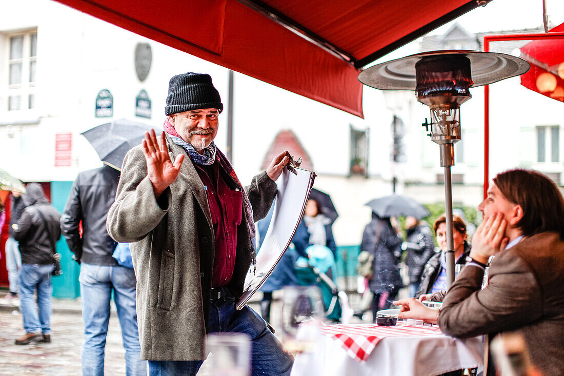 Strassenkünstler redet mit einem Tourist im La Mère Catherine Restaurant, Place du Tertre, Montmartre, Paris, Frankreich, Europa