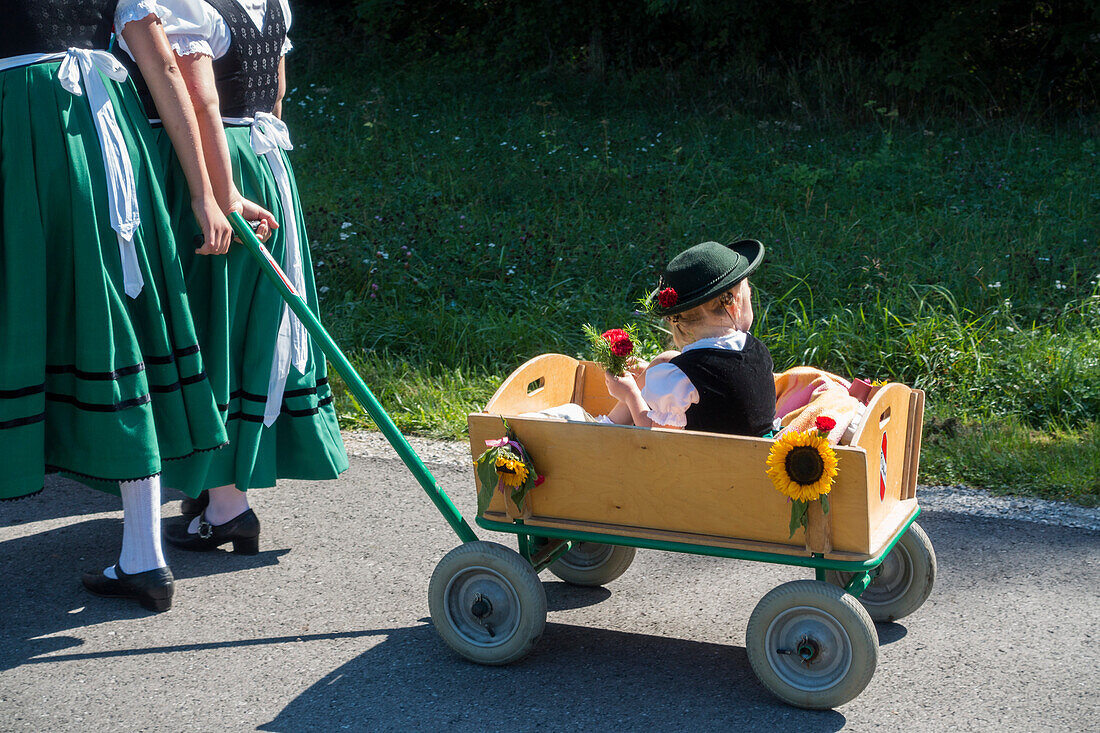 Kleines Mädchen in Tracht in Bollerwagen, Alpenvorland, Oberbayern, Deutschland, Europa