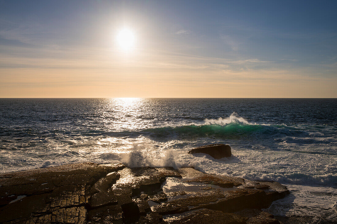 An den Klippen von Kilikee in Irland bricht das Meer in großen Wellen, bei Sonnenuntergang entsteht eine ganz besondere Stimmung, Kilkee, County Clare, Irland, Europa