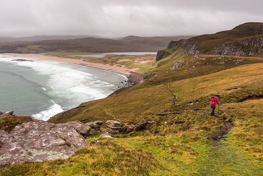 A hiker on the hillside of Sandwood Bay, Highlands, Scotland, United Kingdom