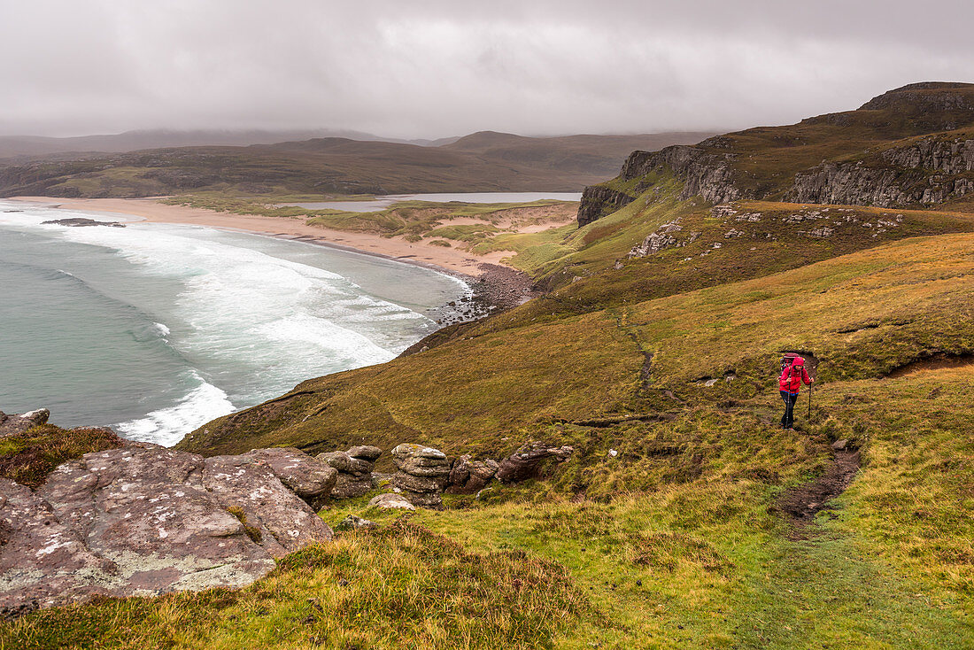 Eine Wanderin am Hang der Sandwood Bay, Highlands, Schottland, Großbritannien