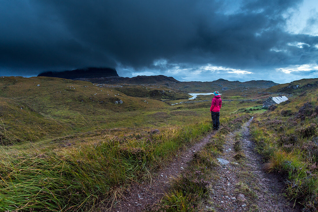 A hiker at Suileag Bothy, clouds in front of the Suilven, Inverpolly Nature Reserve, Highlands, Scotland, UK