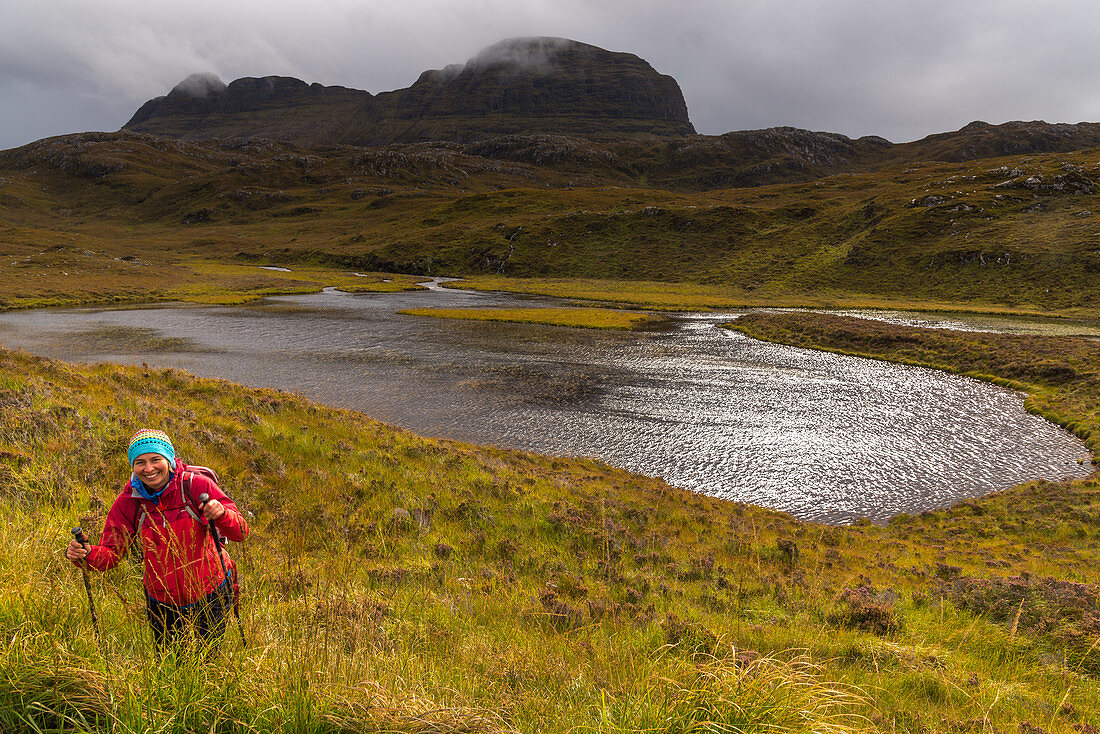 Eine Wanderin an einem Gewässer unterhalb des Suilven, Inverpolly Nature Reserve, Highlands, Schottland, Großbritannien