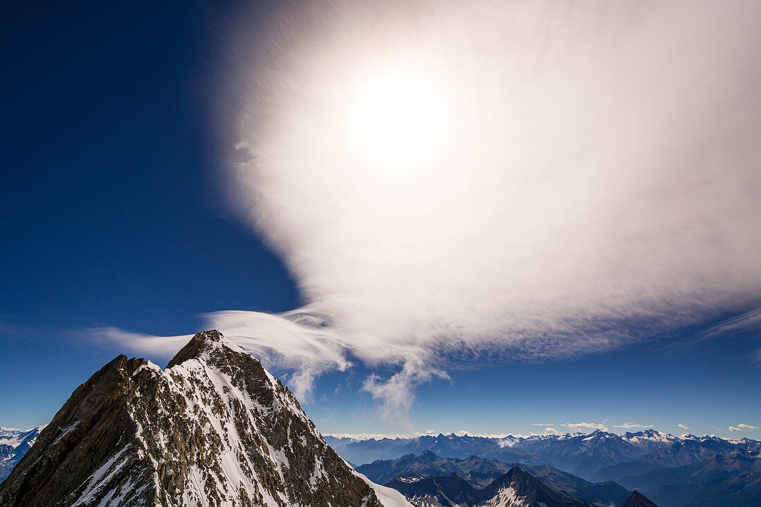 Summit of the Grandes Jorasses with the sun obscuring clouds, Mont Blanc group, France