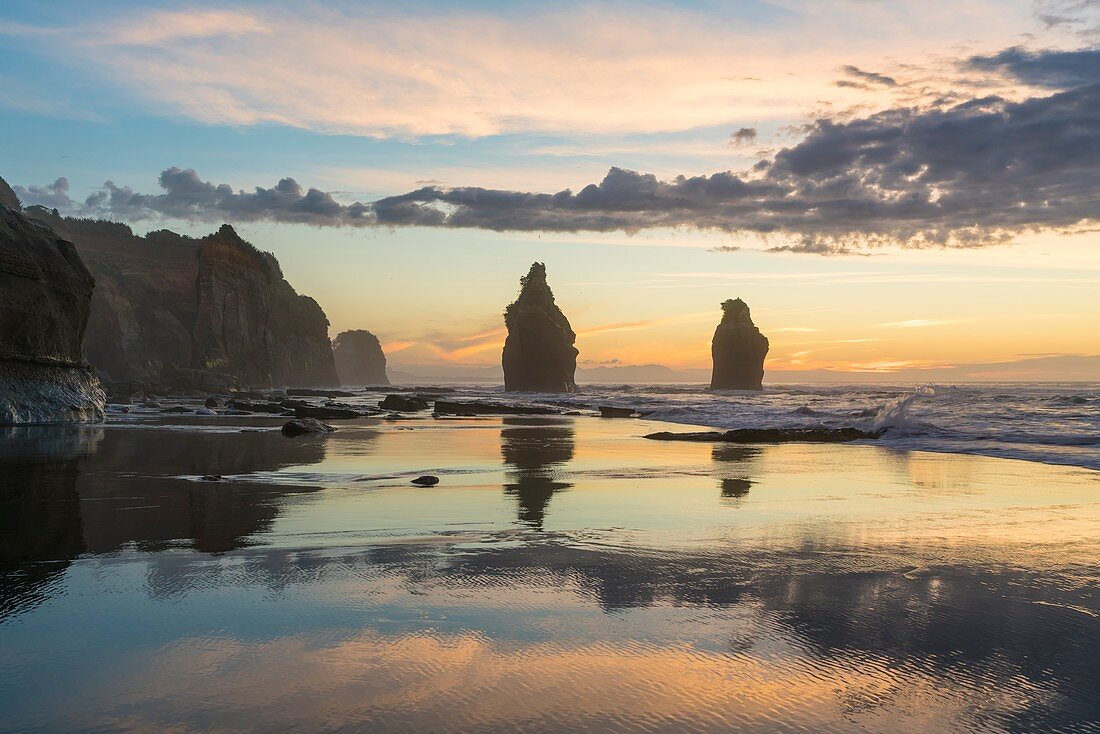 Reflection of the Three Sisters with low tide, at sunset. Tongaporutu, New Plymouth district. Taranaki region, North Island, New Zealand.