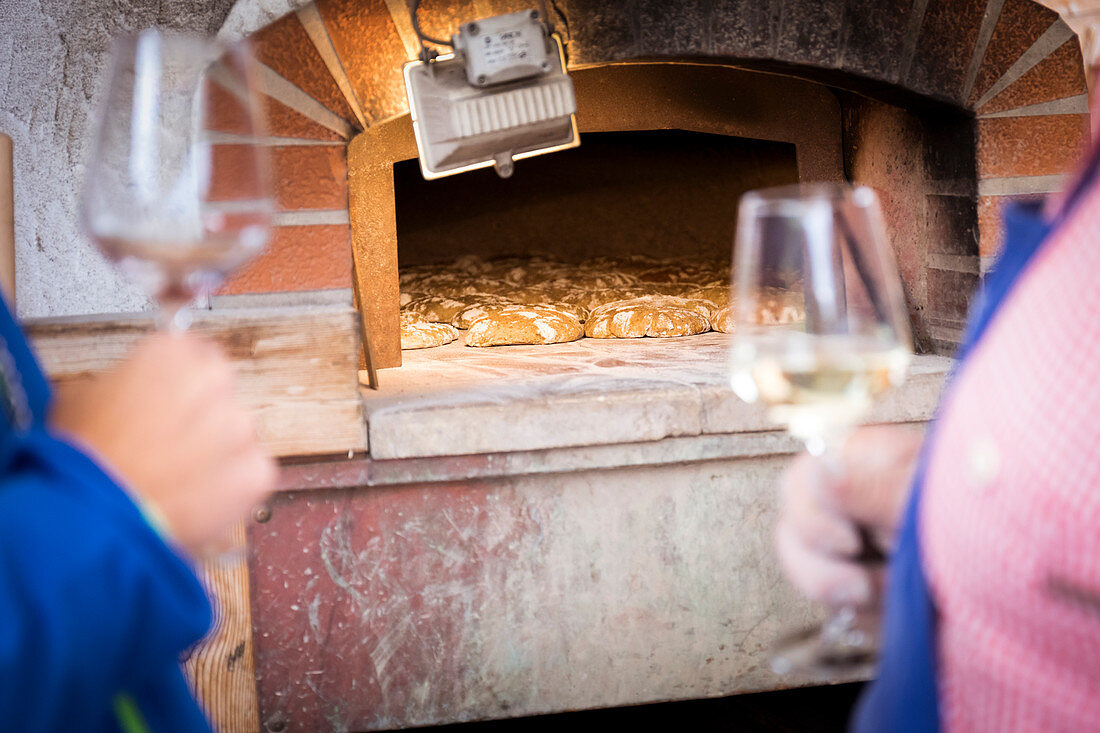 a detail of two glasses of wine with a bread oven in the background, bolzano province;italy;south tyrol;trentino alto adige