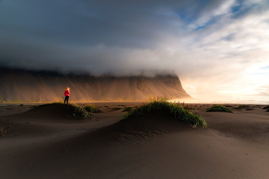 A person looking the the sunrise. Vestrahorn mountain from Stokksness, South eastern Iceland