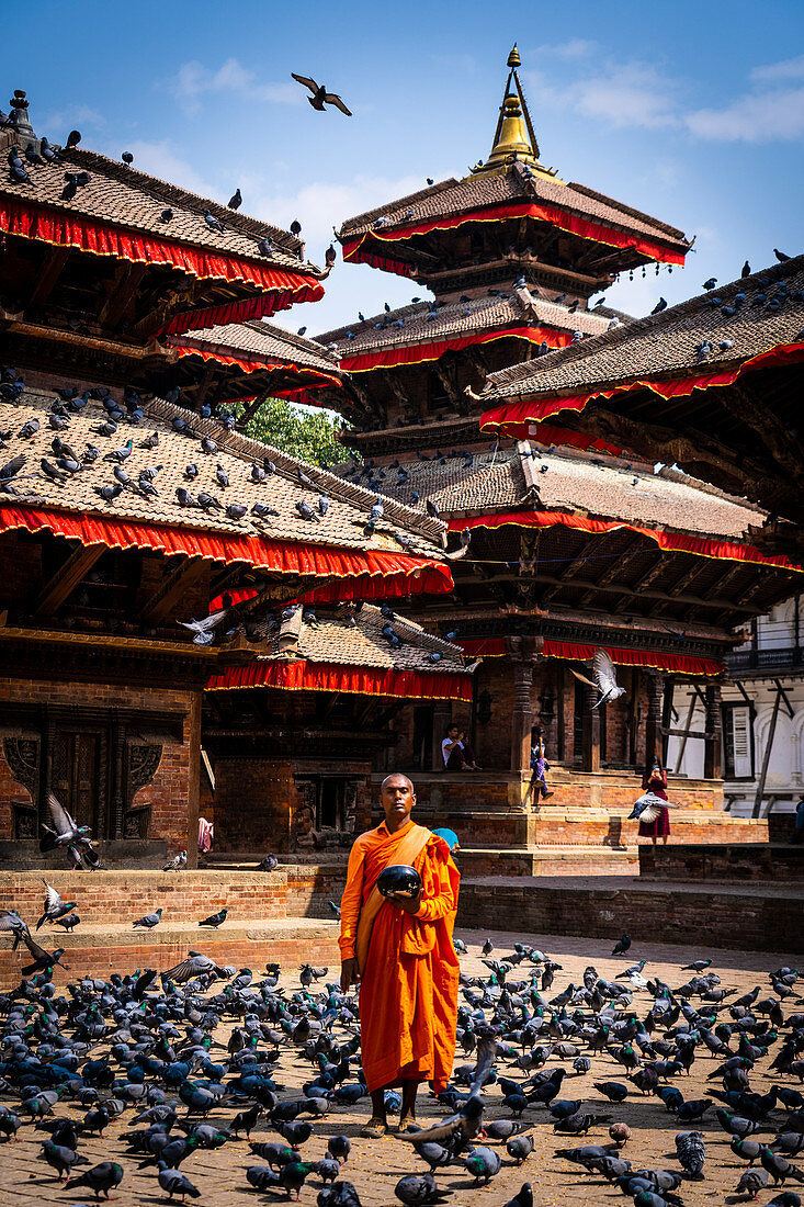 Nepalese Monk wearing orange robe holding urn for alms at Durbar Square Kathmandu, Nepal, Nepalese, Asia, Asian, Himalayan Country, Himalayas.