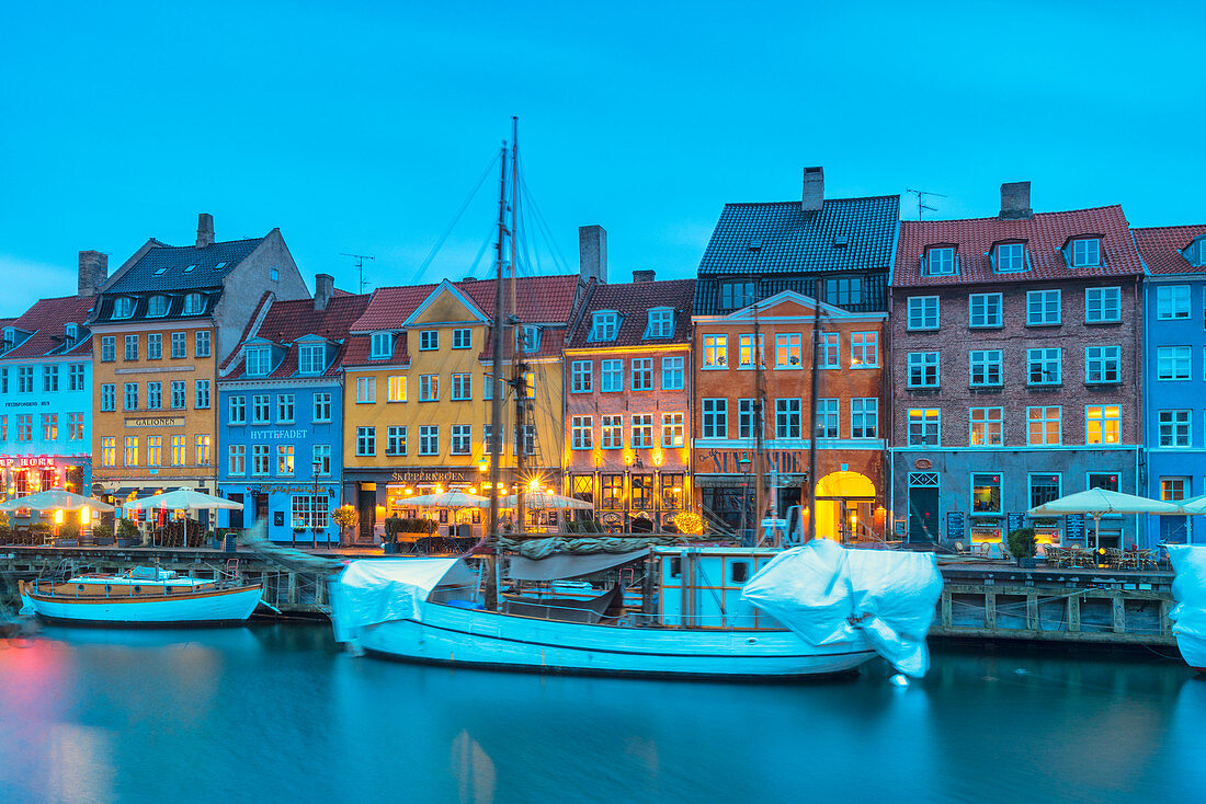 Bunte Gebäude und alte Schiffe entlang Nyhavn-Kanal bei Dämmerung, Kopenhagen, Hovedstaden, Dänemark