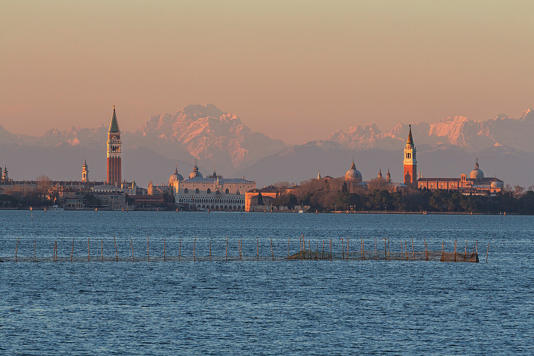 Overview of city of Venice with Dolomites mountains in the background at sunset from Lido of Venice, Venice, Veneto, Italy