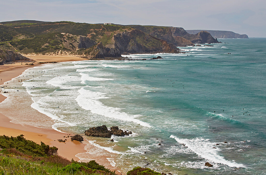 Steilküste und Surfer am Strand Praia de Amado bei Carrapateira, Parque Natural do Sudoeste Alentejano e Costa Vicentina, Atlantik, Distrikt Faro, Region Algarve, Portugal, Europa