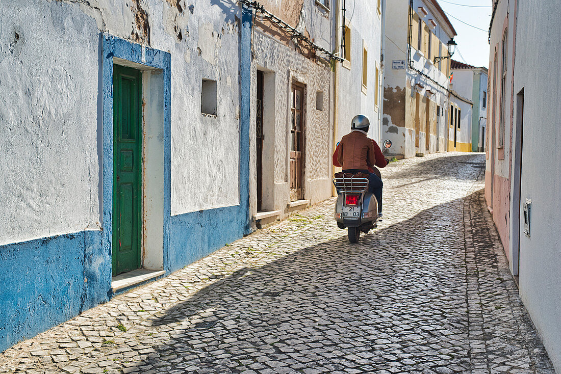 Pärchen auf Motorroller, Vespa, in einer Gasse in Ferragudo, Algarve, Portugal