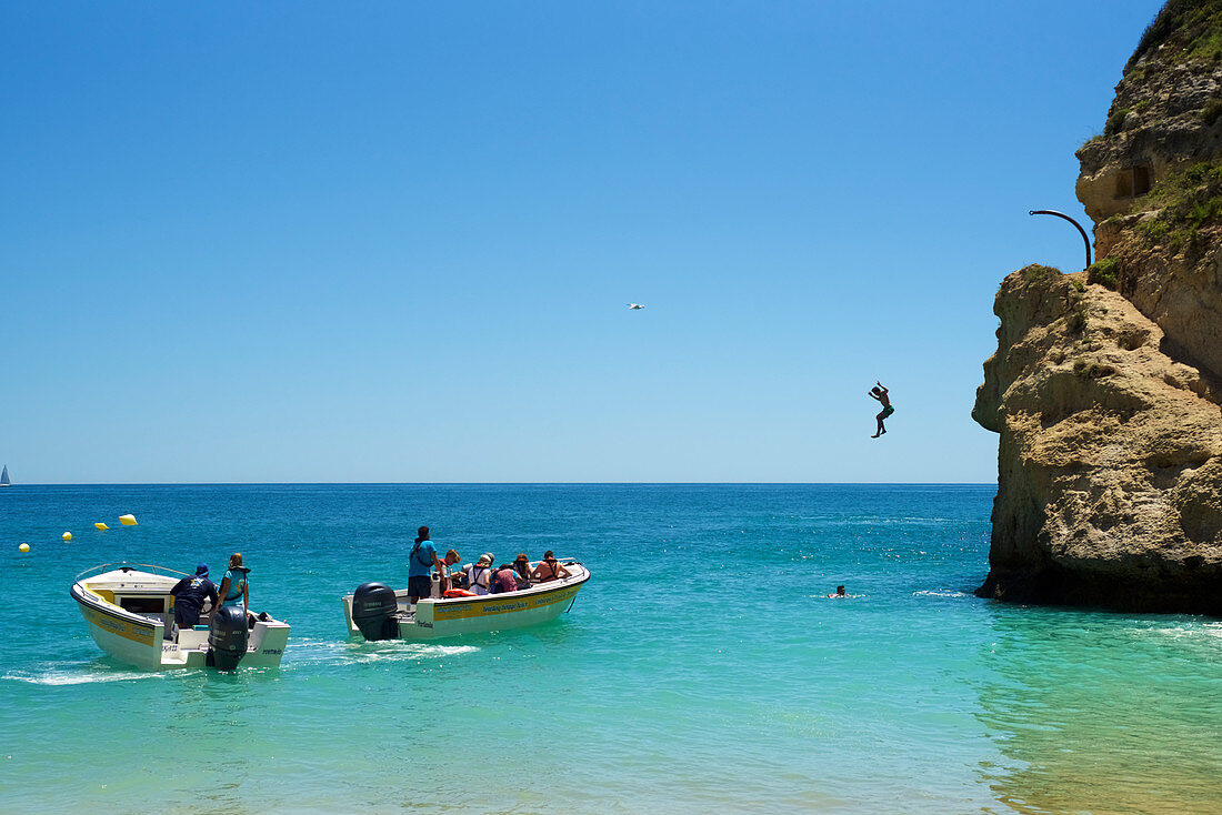 Mann springt von Felsen am Strand von Benagil, Algarve, Portugal