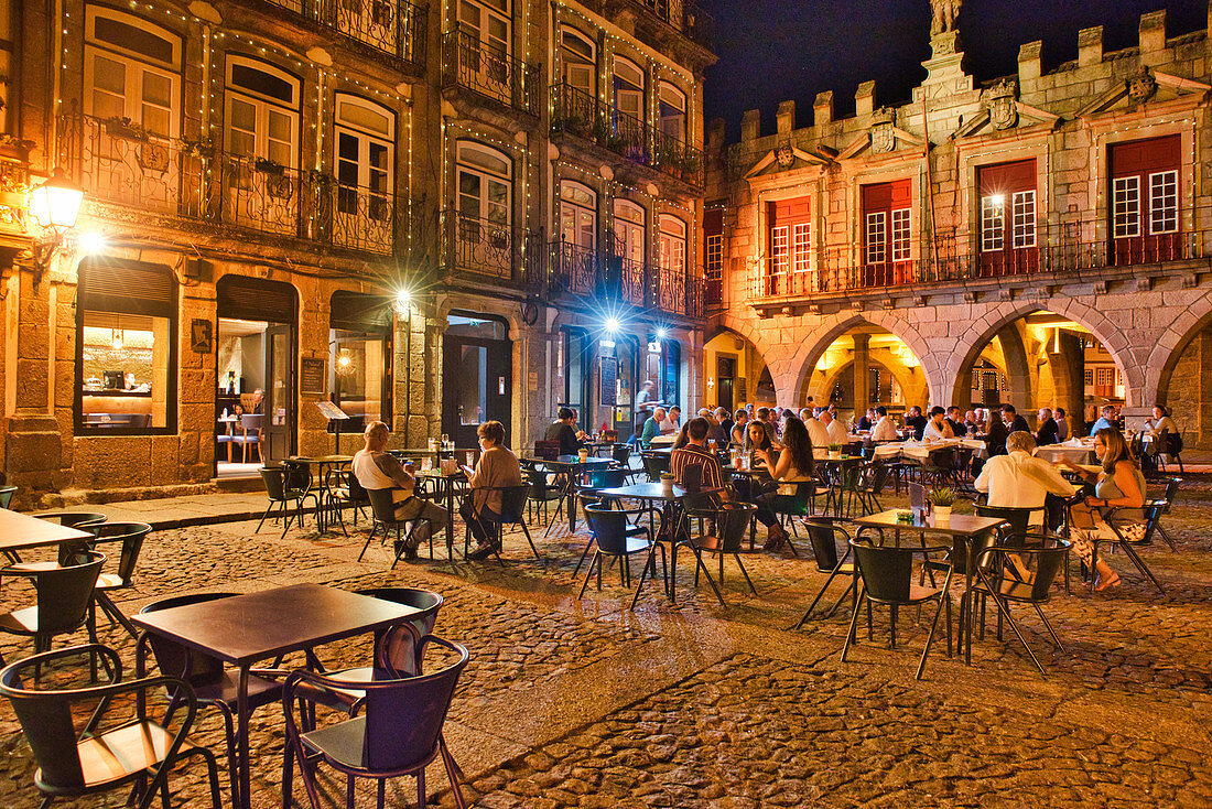 Restaurants und Menschen am Abend auf dem Platz Largo da Oliveira, Guimarães, Minho, Portugal