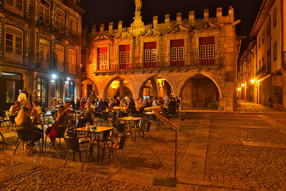 Restaurants und Menschen am Abend auf dem Platz Largo da Oliveira, Guimarães, Minho, Portugal