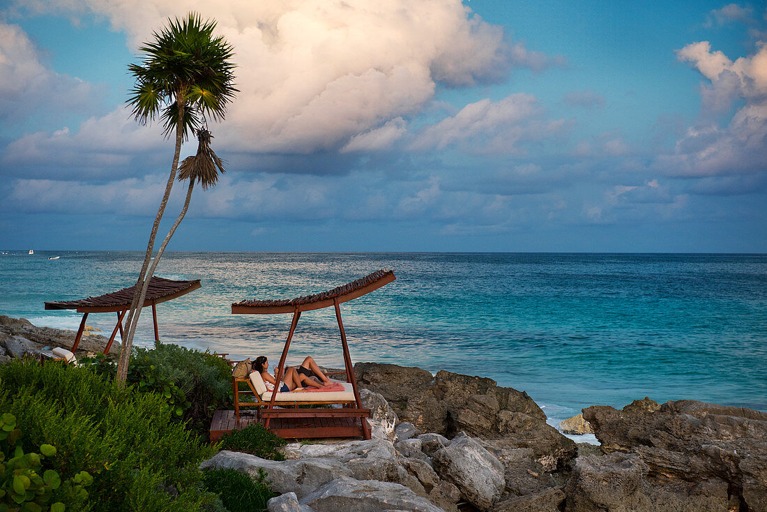 Junges Paar in einer luxuriösen Strandliege eines Hotels dirket am Meer, Tulum, Mexiko