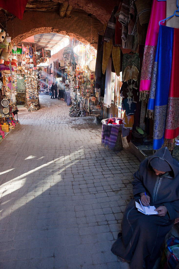 Verkäufer mit traditionellem Gewand vor seinem Geschäft in den Gassen des Souks von Marrakesch, Marrakesch, Marokko