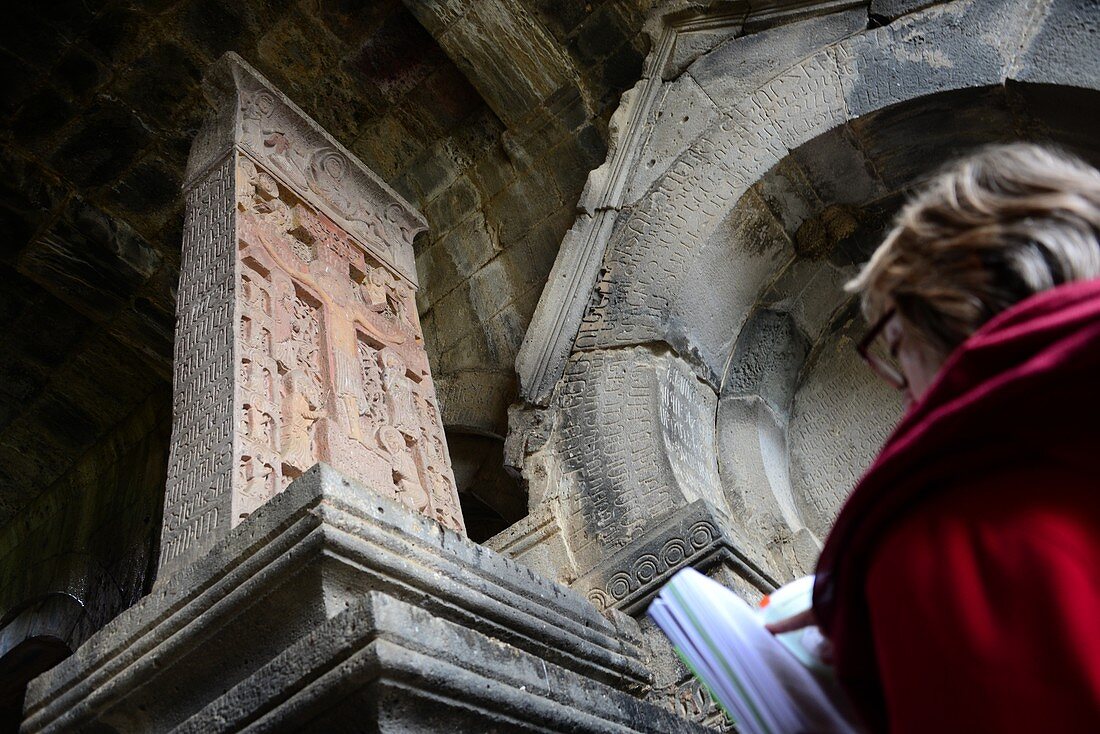 Touristin liest Reiseführer vor einer uralten christlichen Stele, Klosteranlage Haghpat bei Alverdi, Kaukasus, Nord- Armenien, Asien