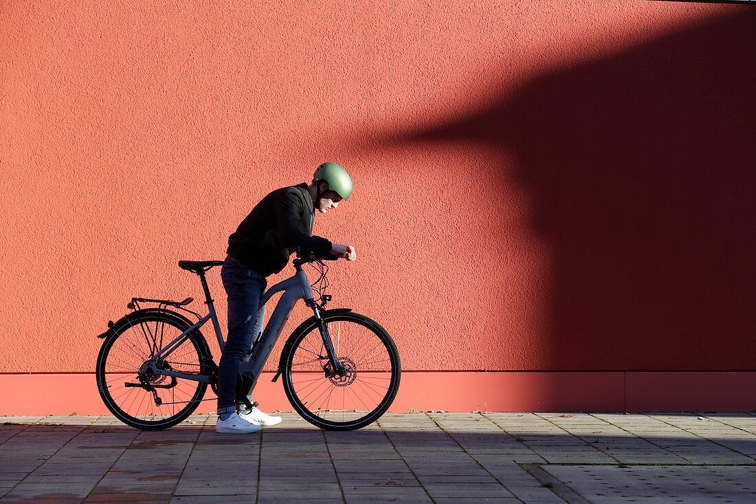 Young man with bicycle in urban environment, Munich, Bavaria, Germany