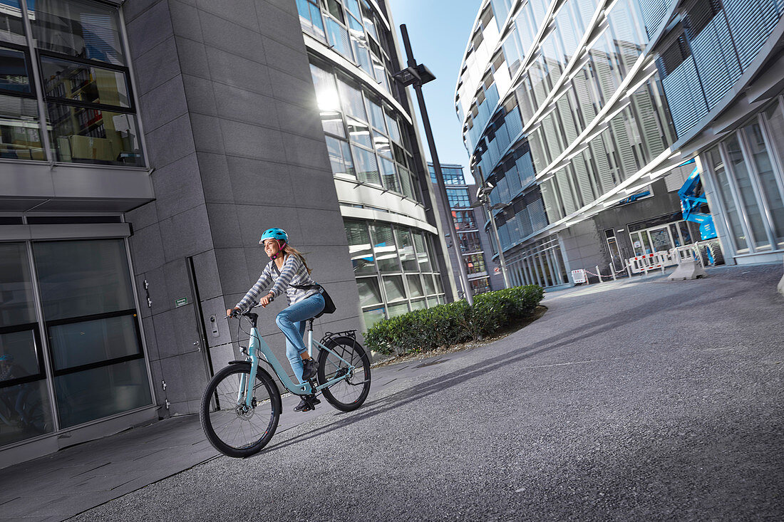 Junge Frau auf Fahrrad in urbaner Umgebung, München, Bayern, Deutschland