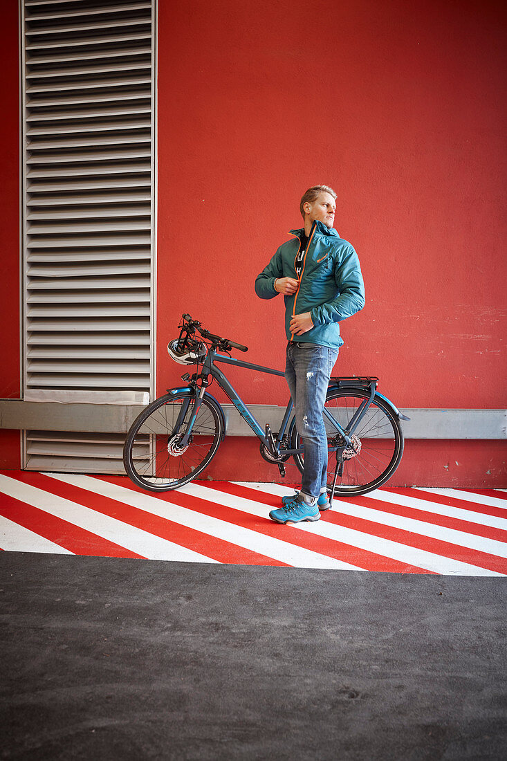 Junger Mann mit Fahrrad in urbaner Umgebung, München, Bayern, Deutschland