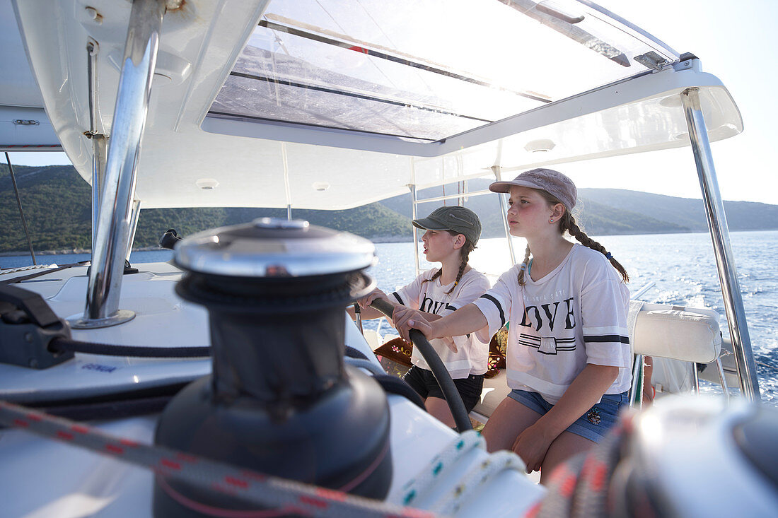 2 girls at the helm, catamaran EOS off the west coast of Cres, Kvarner bay, Croatia