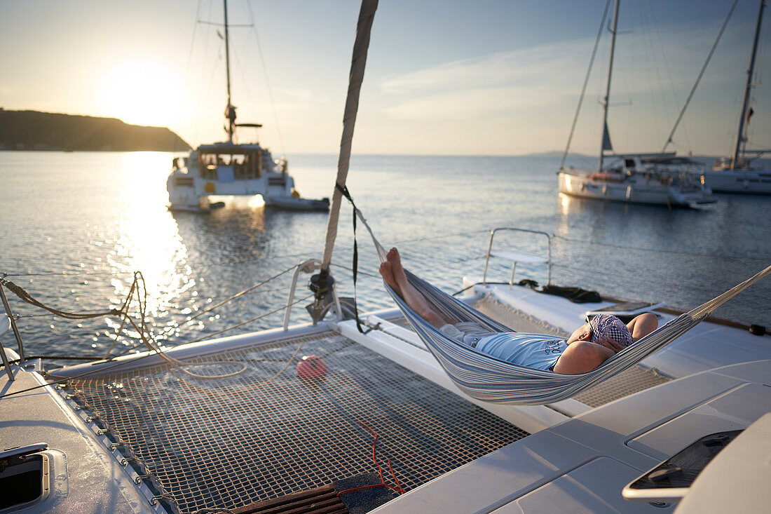 Mann entspannt in einer Hängematte, Katamaran vor Insel Susak, Kvarner Bucht, Adria, Kroatien