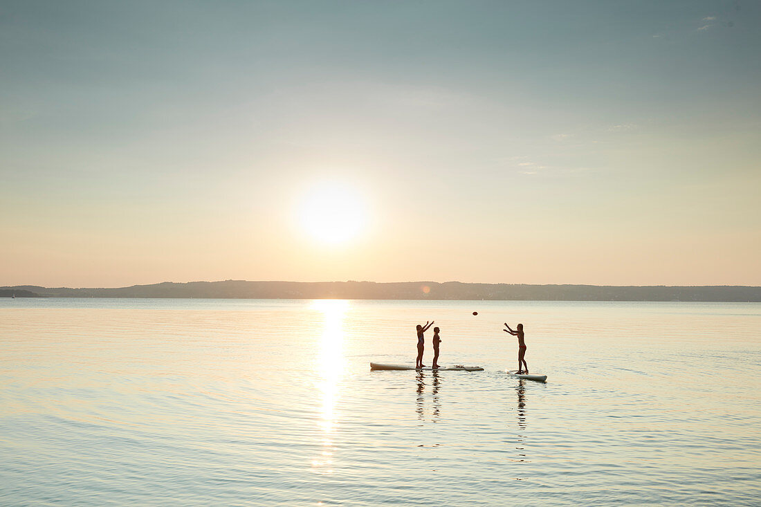 Junge Leute spielen Ball auf ihren Boards, Stand Up Paddling auf dem Starnberger See, Bayern