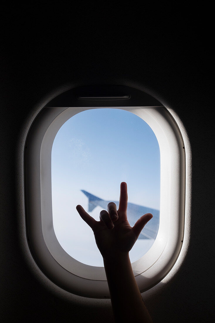 Schattenbild einer Hand, gestikulierend durch ein Flugzeugfenster