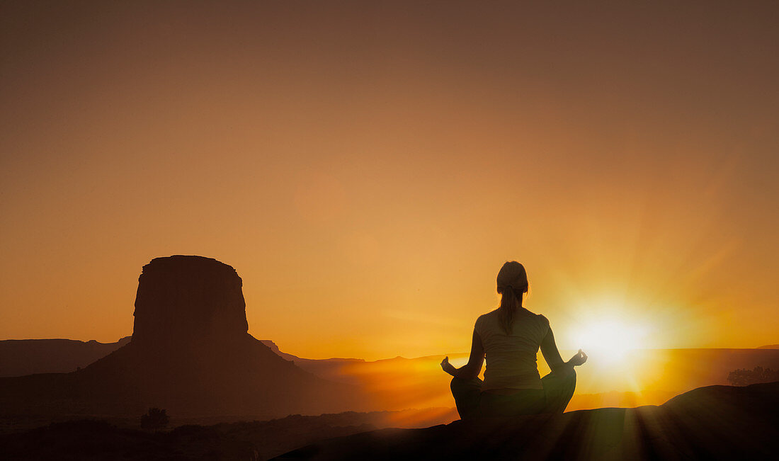 Woman meditating at sunset in Monument Valley Navajo Tribal Park, USA