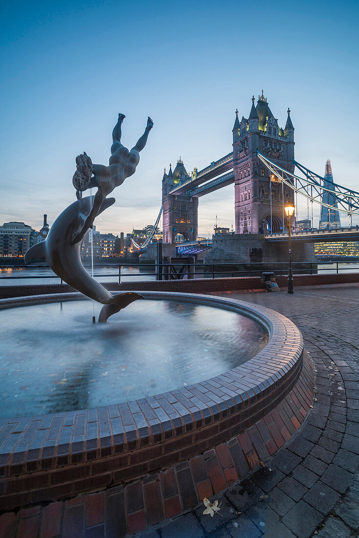 Girl with Dolphin fountain and Tower Bridge at night, St. Katharine's and Wapping, London, England, United Kingdom, Europe